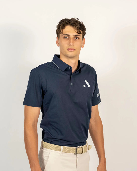 Three-quarter front studio view of a model wearing the navy Aceory Essentials polo with beige trousers.