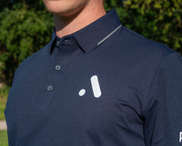 Navy blue polo shirt with a white logo on a blurred outdoor background