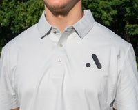 Person wearing a light gray polo shirt with a logo on a golf course