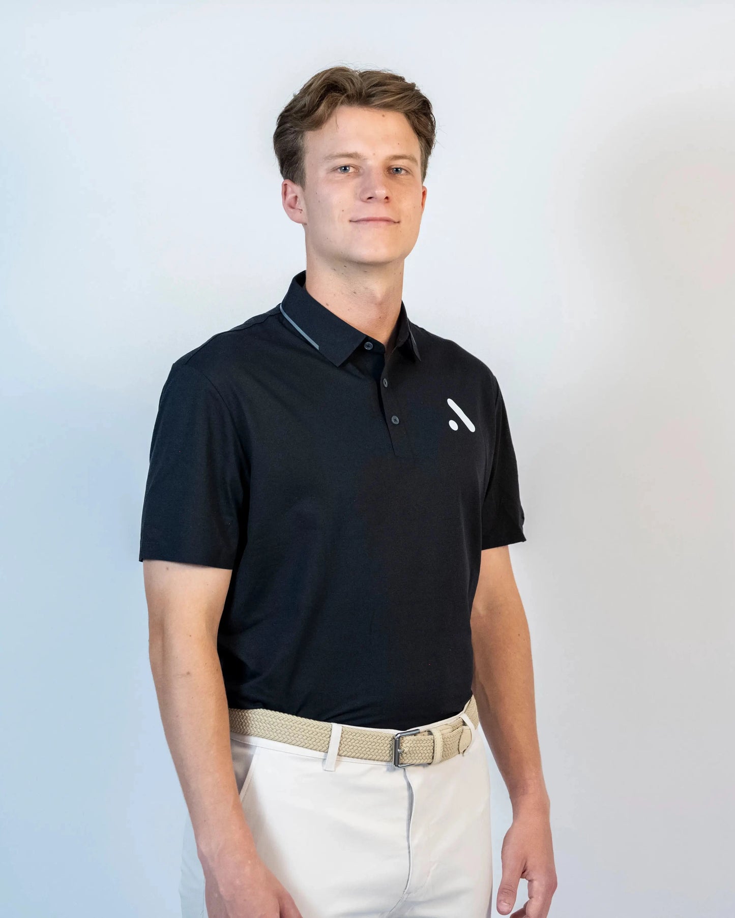 Front view of model wearing the black Aceory performance polo against a neutral studio background.