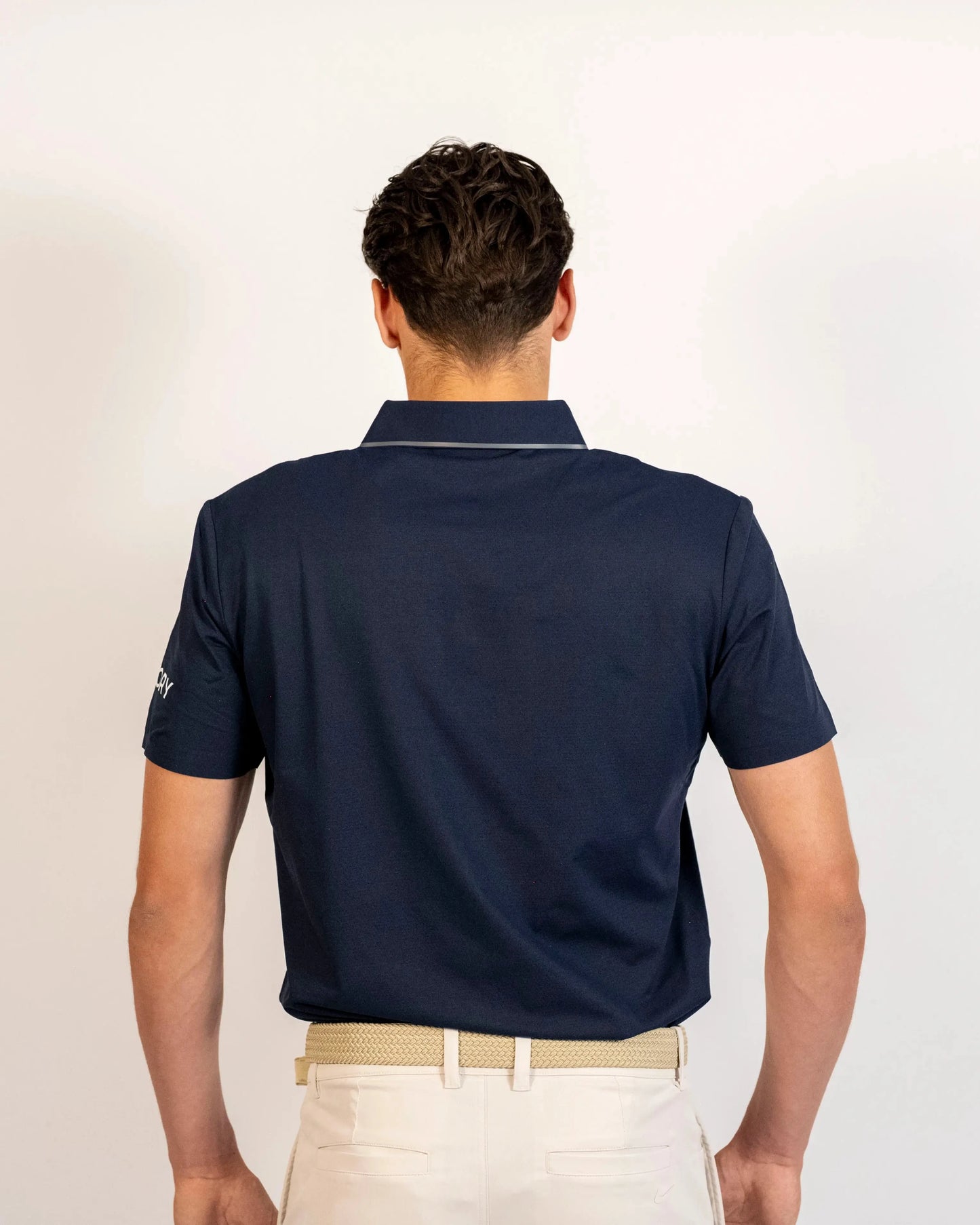 Back view of a model wearing the navy Aceory Essentials polo showing collar and fit.