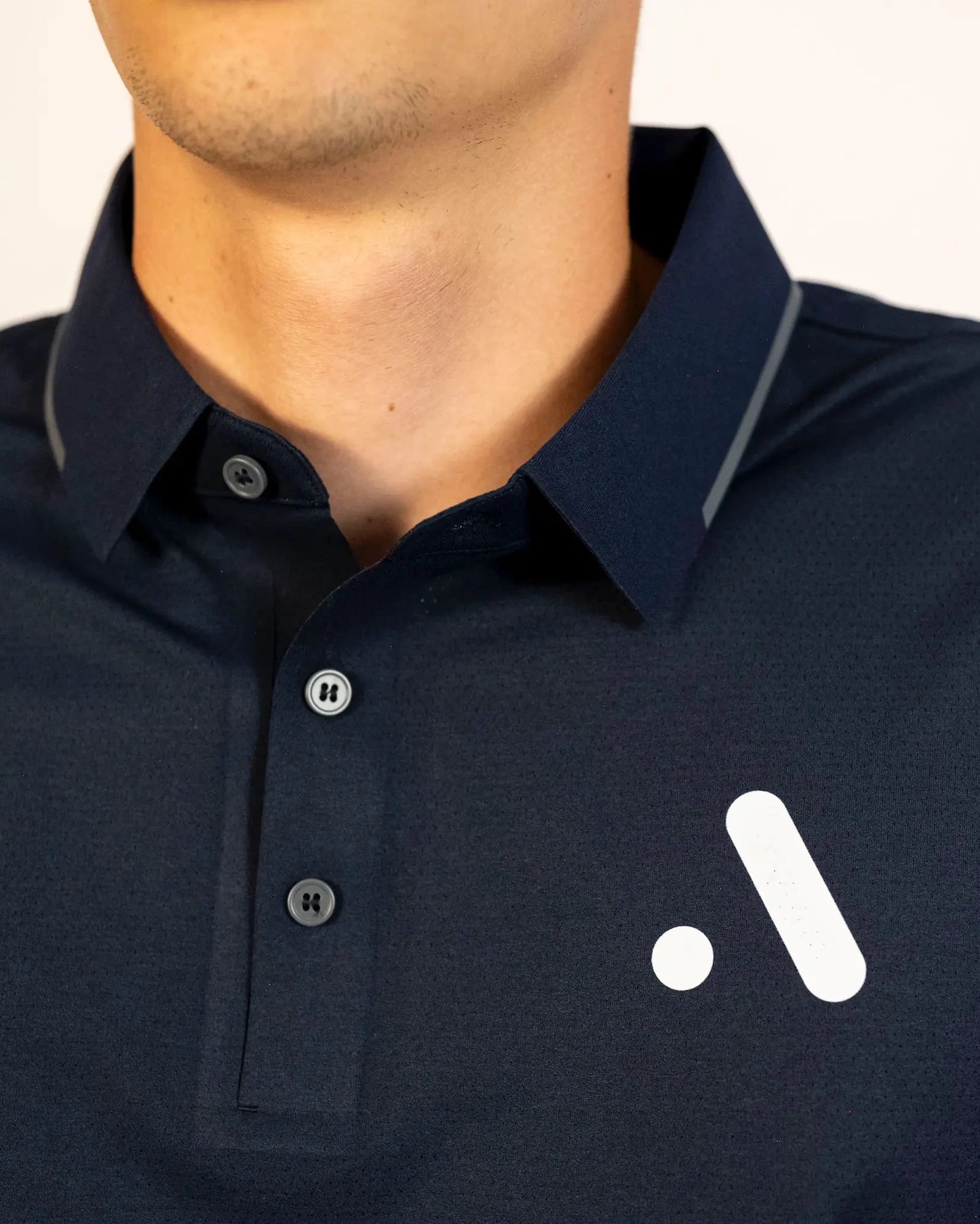 Close-up of the Aceory logo and button placket on the navy Aceory Essentials polo.