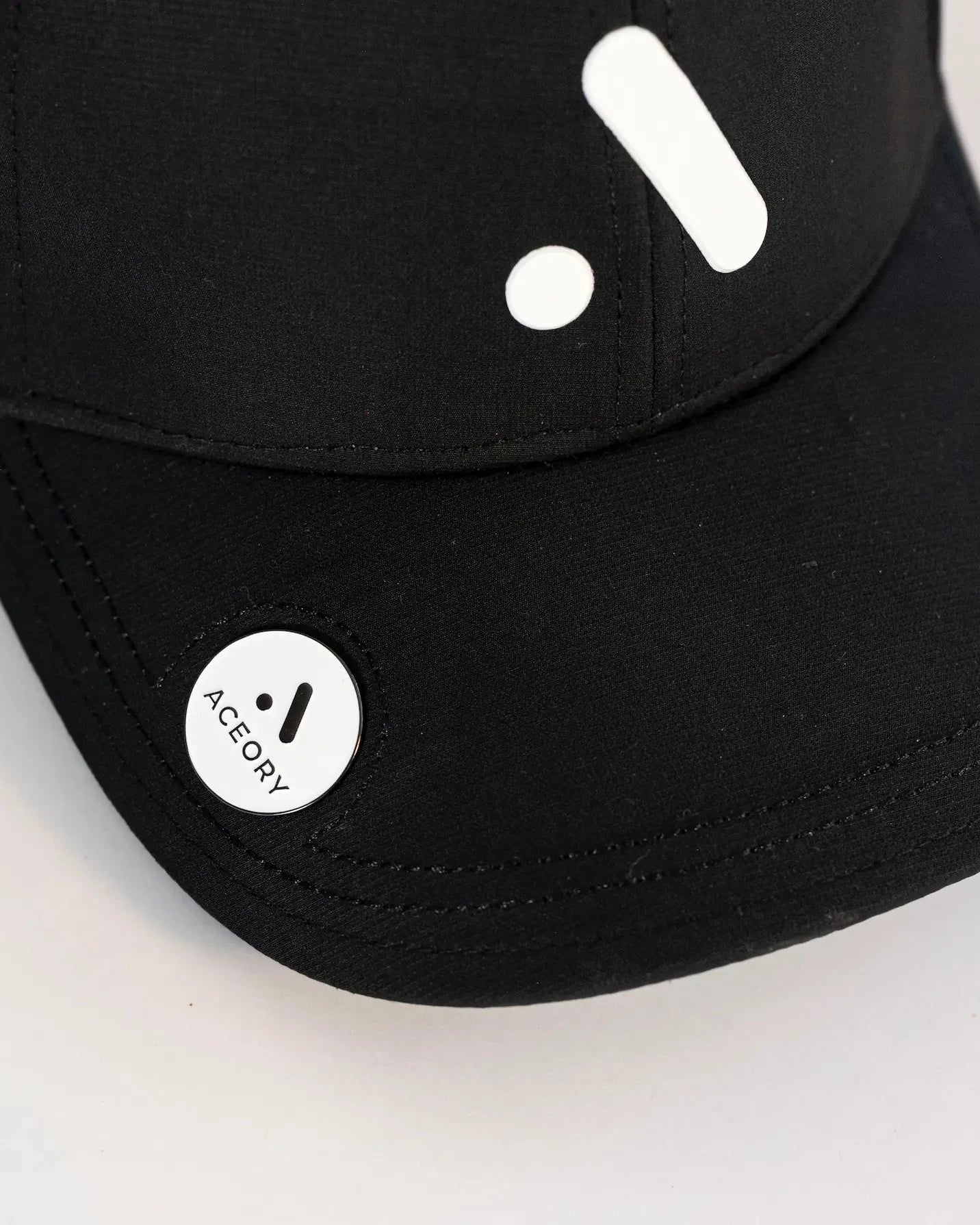 Close-up of the Aceory golf cap brim featuring the magnetic ball marker.