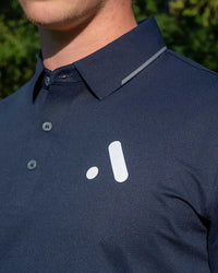 Outdoor close-up of the Aceory logo and collar detail on a navy essentials polo.