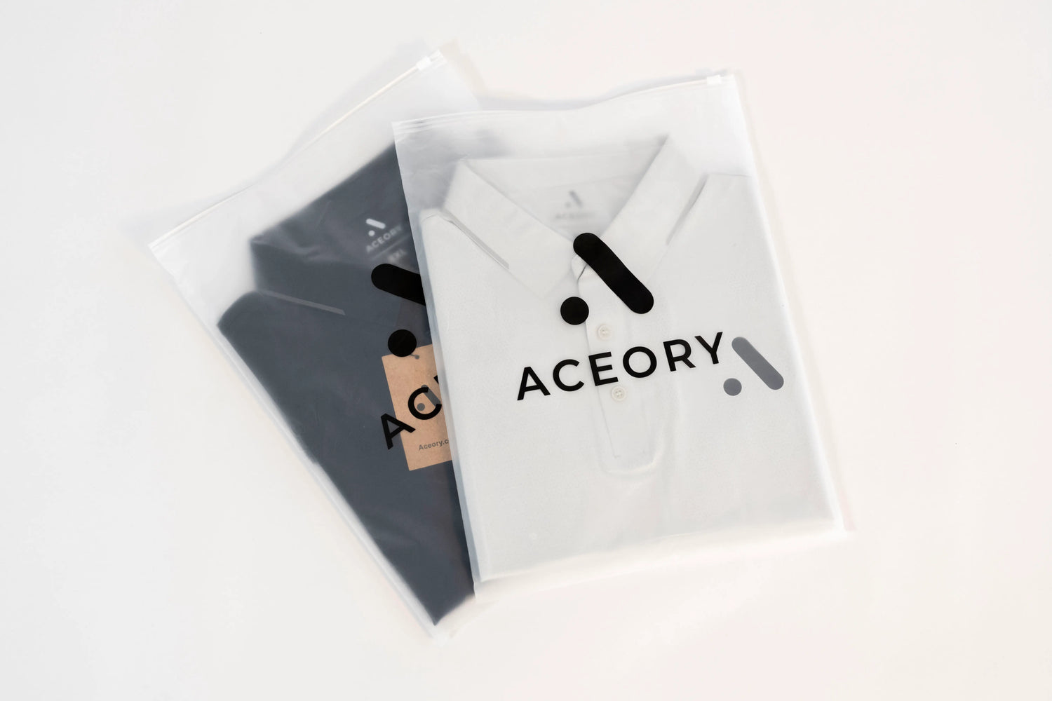 Two Aceory polo shirts in branded resealable packaging, black and light grey.